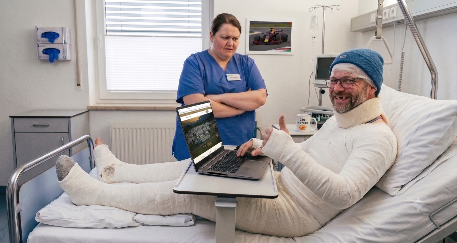 Bandagierter Camping-Gast im Krankenhausbett bucht am Laptop – dank fairer Stornobedingungen am Schitterhof CAMPING WEISS